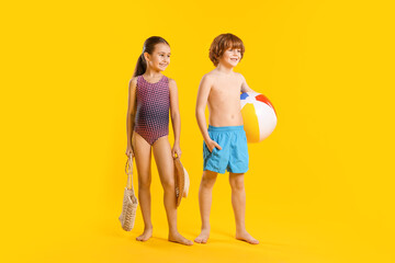 Fototapeta premium Children in swimwear with beach accessories on yellow background