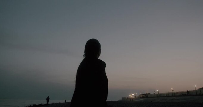silhouette of a person dancing alone on the beach at twilight