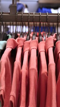 Colorful cotton polo shirts hanging on hangers in a row for sale in a clothing boutique, highlighting the concept of consumerism, fashion, and retail business in a shopping mall