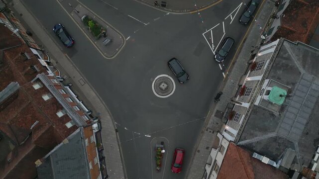 Aerial view of a quiet street intersection with cars, buildings, and decorative elements.