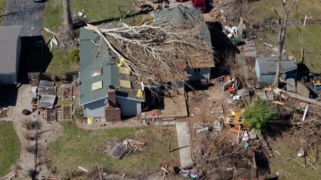 Drone aerial view of residential neighborhood destruction after a tornado with damaged houses and scattered debris.