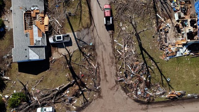 Drone top down shoot of residential neighborhood destruction after a tornado with damaged houses and scattered debris.