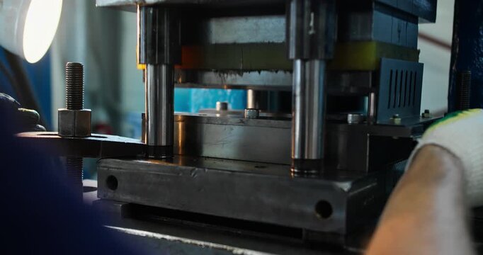 Blue collar worker performing metal stamping operation in factory. Industrial job and heavy manufacturing concept