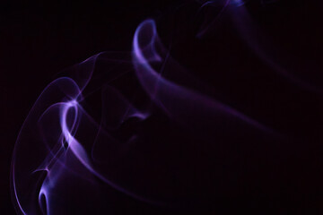 Soft purple smoke swirls gently against a dark background creating an ethereal atmosphere © Claudio Bórquez
