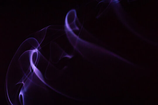 Soft purple smoke swirls gently against a dark background creating an ethereal atmosphere