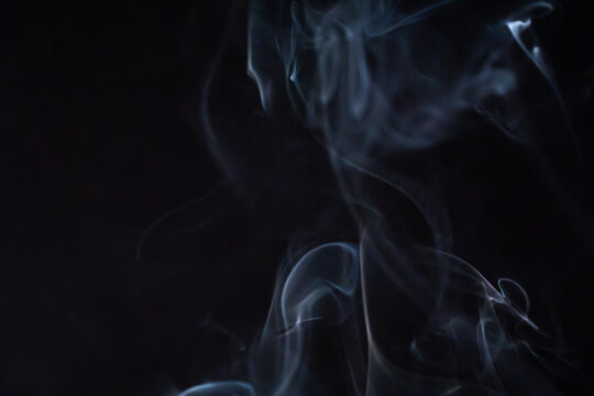 Soft wisps of smoke rise gracefully against a dark background