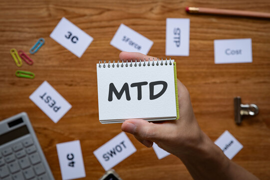 Eye-catching image of MTD text on notebook. The word stands for month to date. Shown with calculator, clips, pen.