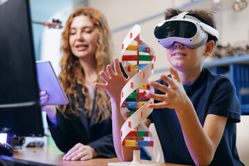 Naklejka premium Student using vr headset exploring dna model with teacher in classroom, AI intelligence technology for children in school