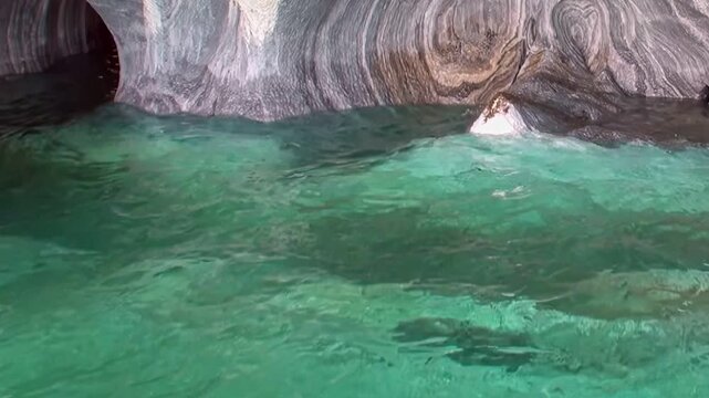 Immerse in the serene beauty of Patagonia's Marble Caves. Turquoise water gently ripples against naturally sculpted rock, revealing intricate patterns and a mesmerizing glow.