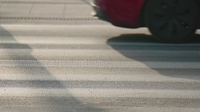 Cinematic slow motion shot of cars driving along city street. Close-up view of vehicles passing on urban road. Modern city transportation, everyday traffic and urban mobility concept in daylight