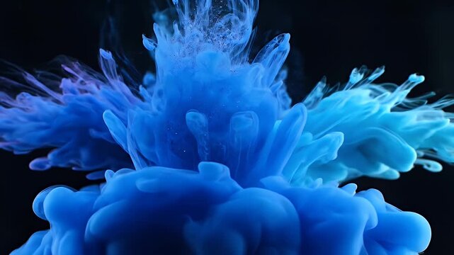 Abstract image of blue ink swirling in water against a dark background, creating dynamic shapes