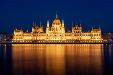 Fototapeta premium The Budapest Parliament building at night on the Danube river bank
