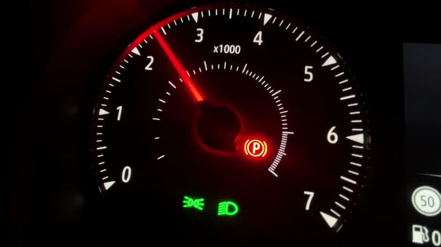 Video of Close up of illuminated car tachometer dashboard at night, red needle indicator, glowing parking brake warning symbol, modern vehicle instrument panel, automotive technology concept