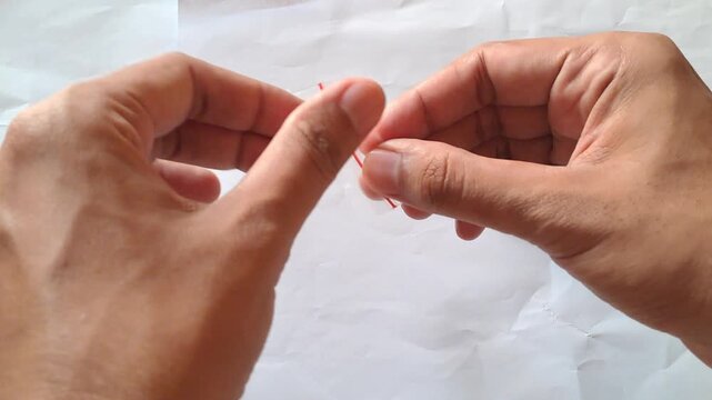 Close-up of Asian male hands demonstrating the dangers of illegal drugs using capsules and a small plastic bag of white powder as visual aids for drug abuse prevention education.