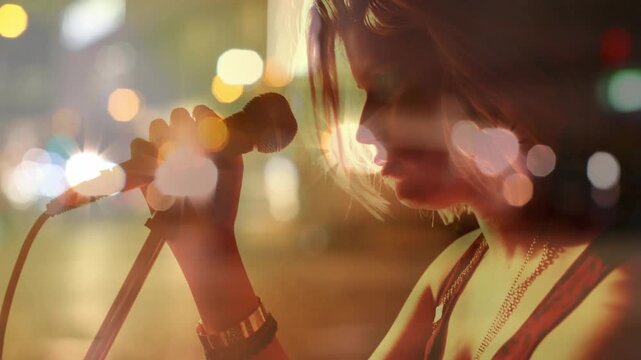 Female singer adjusting mic grip, drawing mic close and singing against warm bokeh lights for music
