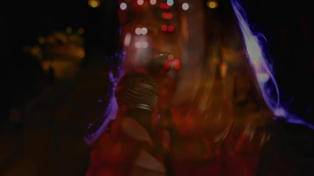 Vertical video: Shot panning lead singer emerging singing to mic for music while car lights overlay