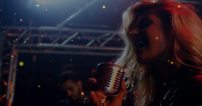 Vertical video: Singer leaning into retro mic, singing music, sparks drifting and guitarist playing