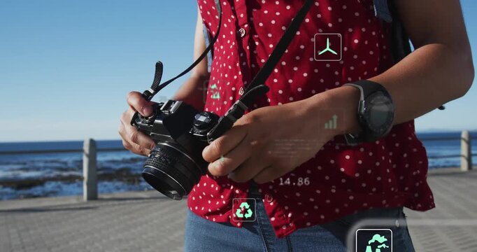 Vertical video: Female camera user adjusting dials, AR icons showing CO2 water wind coastal data