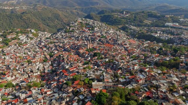 Aerial view revealing the city of Taxco, Guerrero, Mexico on a sunny day with tiled roofs and colonial architecture.
