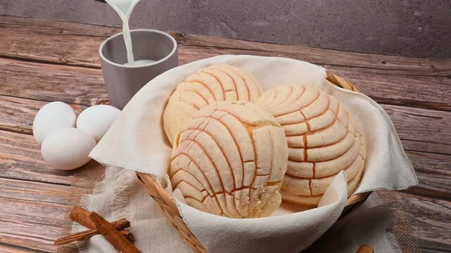 Sweet Mexican pan de dulce concha with milk pouring into a cup, rustic background