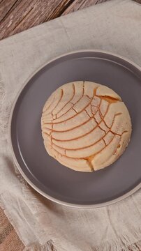Typical Mexican bread, a vanilla concha isolated on a plate and rotating camera