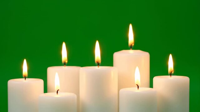 A group of varying height pillar candles, their flames gently swaying in unison on green screen element, organic movement, unison