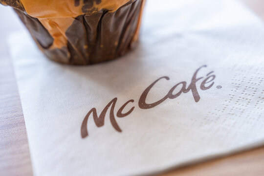 Belgrade, Serbia: July 3, 2024: Close up of a McCafe paper napkin printed with mccafe logo beside a wrapped muffin, shallow depth of field on a table, warm light highlighting paper texture, folds