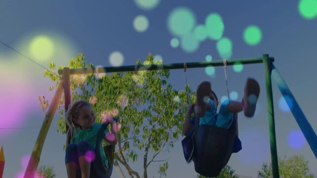 Two children appearing then pumping and swinging for play, bokeh overlays drifting over swings