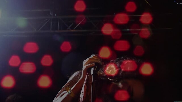 Singer performing music with mic, hitting note causing hair whipping while red bokeh overlays