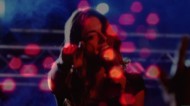 Camera shifting singer singing in mic, pointing to engage concertgoers amid red hex bokeh overlay