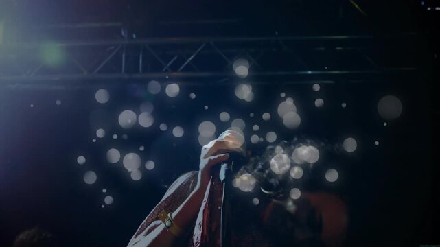 Female singer performing on dark music stage, singing into mic and causing layered bokeh building
