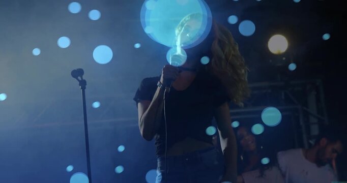 Female singer hearing music cue whipping settling singing with mic as blue dots drifting over lens
