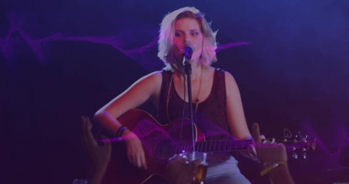 Singer bringing mouth to mic and playing guitar, singing to engage music fans, purple waves pulsing