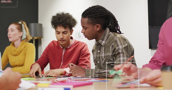 Two men sorting paper and folding green piece, leaning in, guiding assembly in craft workshop