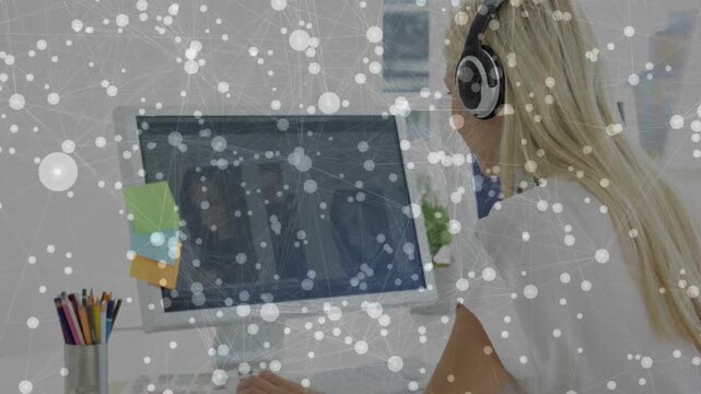 Woman leaning forward, typing on keyboard for focused office work, particles drifting over hands