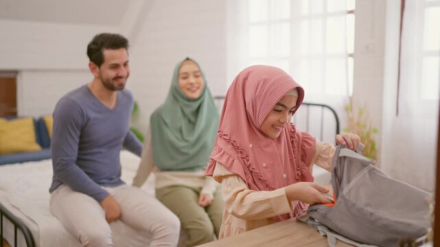 Asian Muslim mother prepare school backpack to young daughter at home.