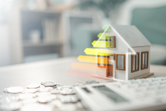 Energy efficiency rating displayed on a model house with calculator and coins, representing home energy audit, cost savings, and sustainable housing. Concept of energy conservation.