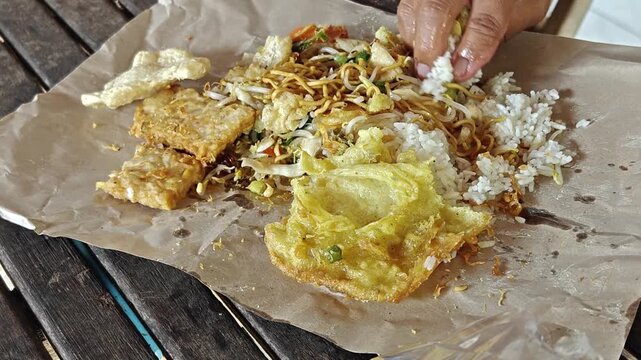Traditional Indonesian Nasi Campur Wrapped in Brown Paper with Tempeh and Egg