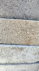 Obraz premium Close-up of a rough brick wall texture with visible cement mortar lines and granular surface detail. The natural variation in color and texture creates an authentic, rustic look