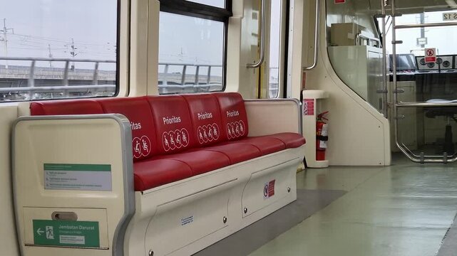 Bekasi, Indonesia - March 21, 2026: Priority seating area with red leather chairs and accessibility icons inside a modern Indonesian commuter train carriage