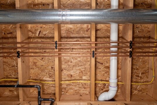 Exposed plumbing and HVAC ductwork in unfinished basement ceiling