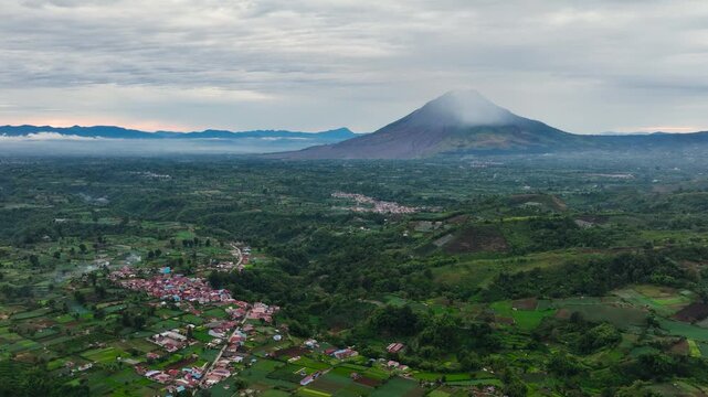 Berastagi city among farmland and Sinabung volcano at sunset. Sumatra, Indonesia.