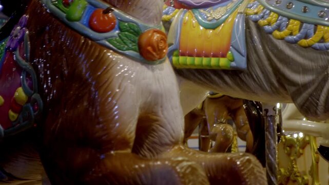 Slow motion panning close-up view of a painted carousel horse figure on a festival ride, showing bright decoration and fair atmosphere