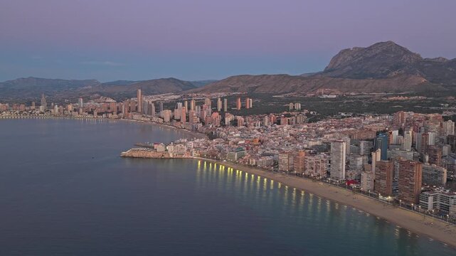Majestic aerial view of the benidorm skyline in spain at twilight. The city lights are turning on along the poniente beach and coastline