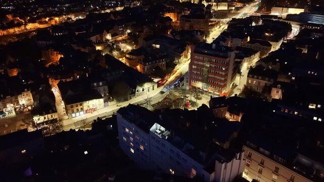 Central Le Mans at night, likely near Place de la Republique, revealing illuminated streets, city blocks and downtown landmarks in Sarthe, Pays de la Loire, France, Slow drone glide