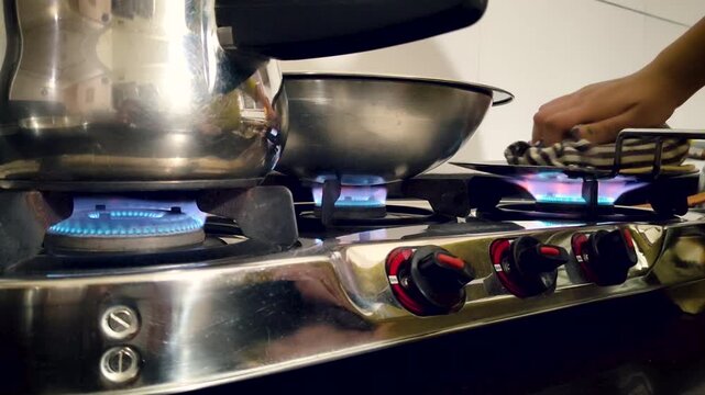 Gas stove burners with blue flame, steel utensils and flatbread cooking in home kitchen. Useful for cooking using LPG gas, household, energy and domestic lifestyle content.