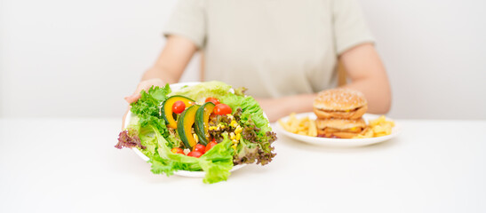 Naklejka premium happy woman choose vegetables Salad. Healthy and Unhealthy Food Choice, Comparison of Calories and Nutrition of vegetables and Hamburger. diet planning, weight loss control, junk food and lifestyle
