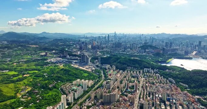 Panoramic aerial view of Shenzhen cityscape and lush green hills under blue sky, Guangdong province, China.