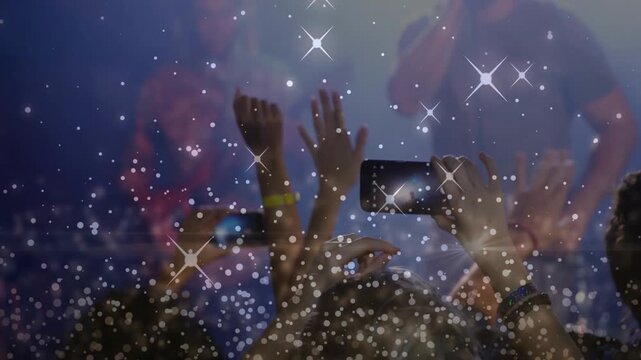 Concert artist gesturing, crowd responding holding phones and waving hands front, overlay sparkling