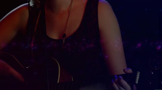 Teen musician playing acoustic guitar, camera rising showing mic, performing with pink particles